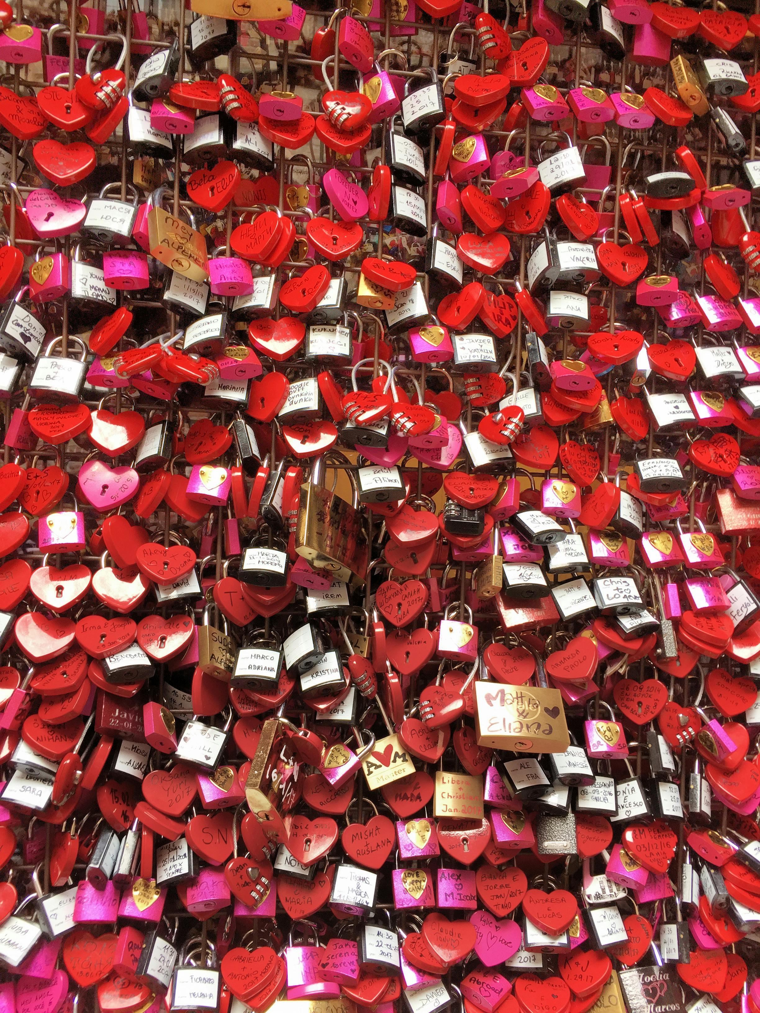A vibrant wall of heart-shaped love padlocks symbolizing romance in Verona, Italy.