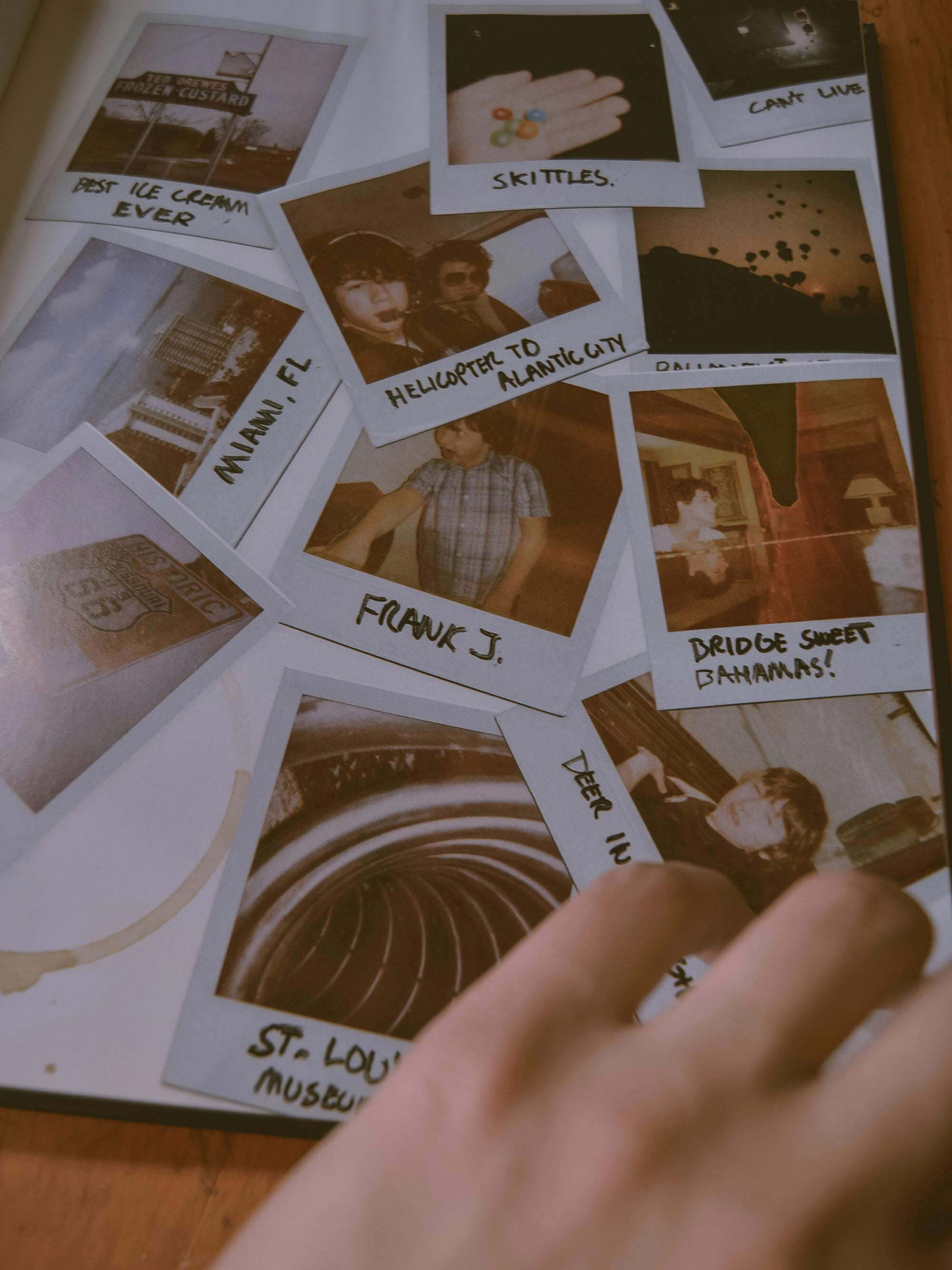 A close-up of a hand flipping through a vintage Polaroid photo album.