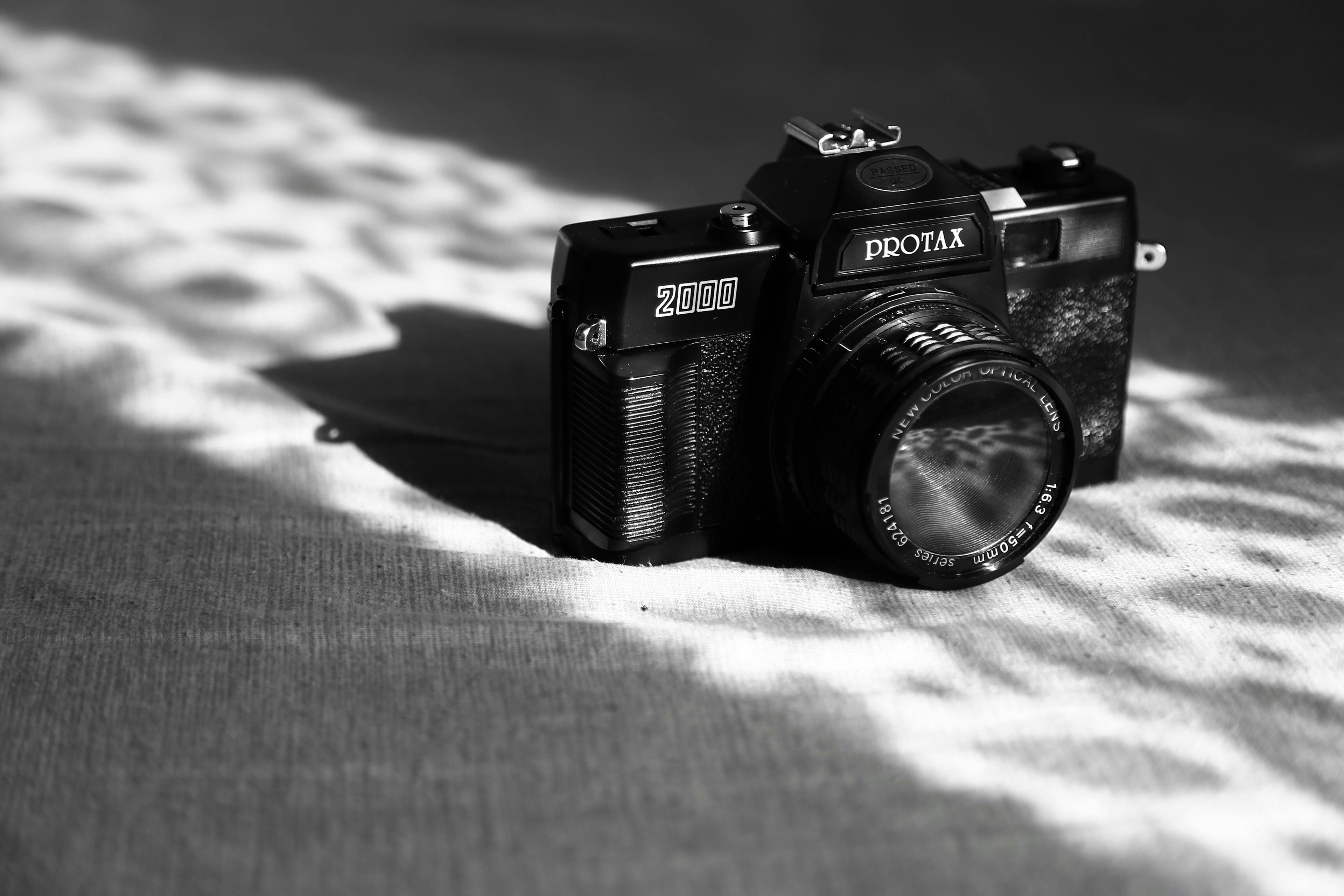 Close-up of a vintage camera with lens, showcasing intricate details and artistic shadows.
