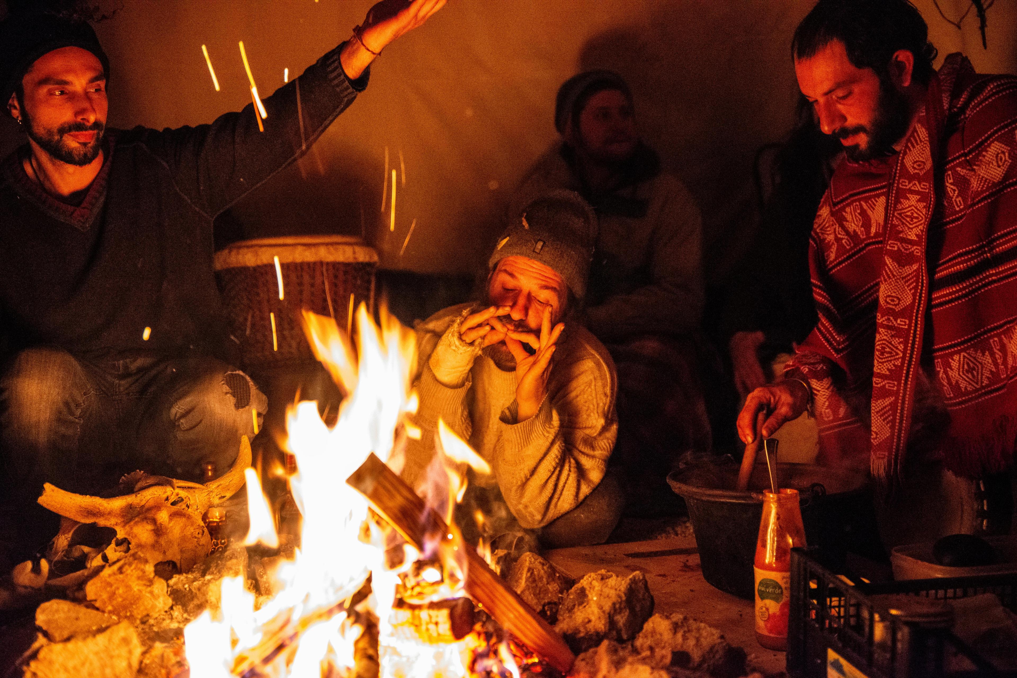 Relaxed group enjoying campfire warmth and togetherness at night.