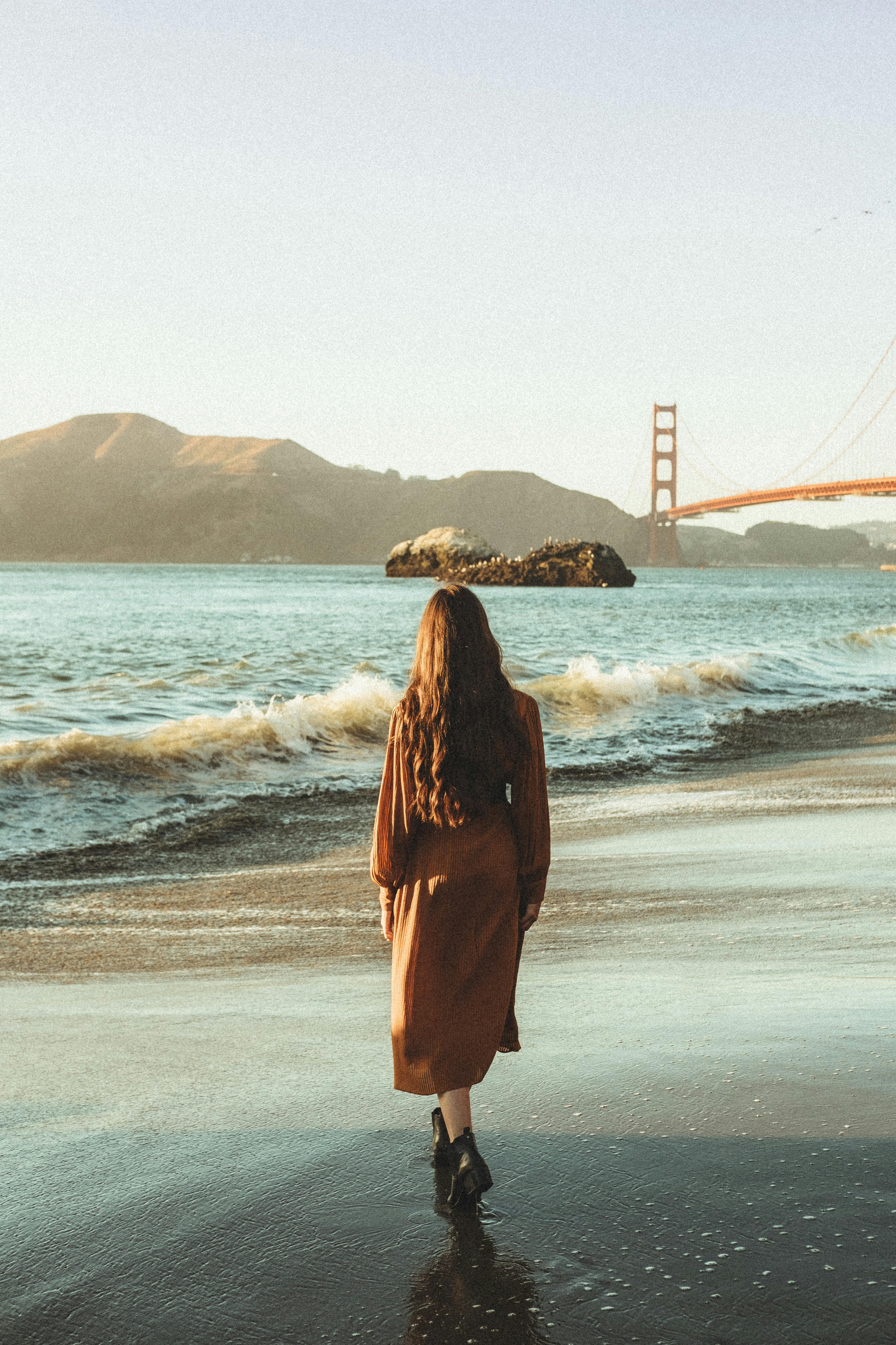 Back View of a Woman Wearing Brown Dress Walking on the Beach