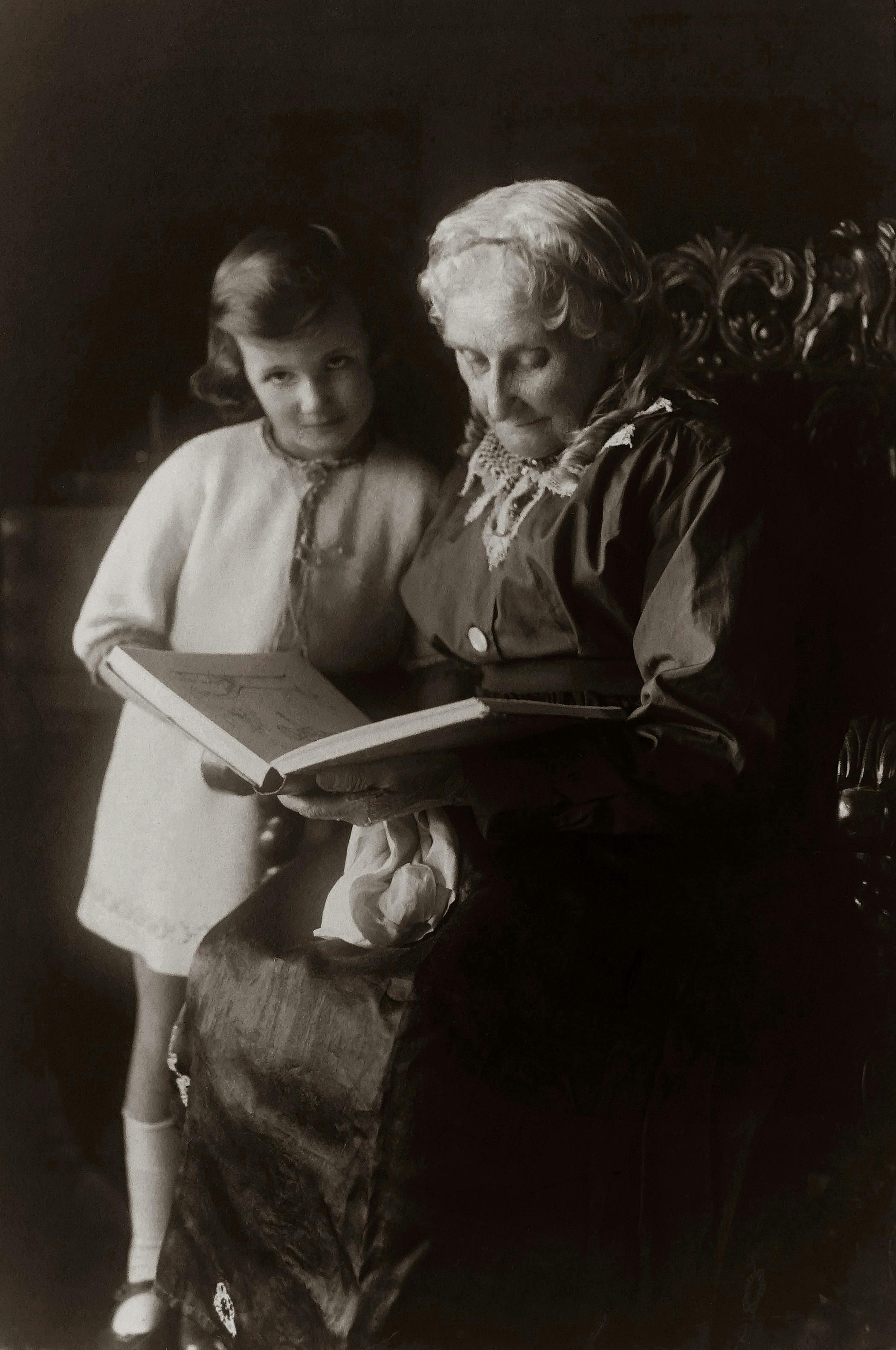 Old Woman Sitting on Chair And Reading A Book To A Child