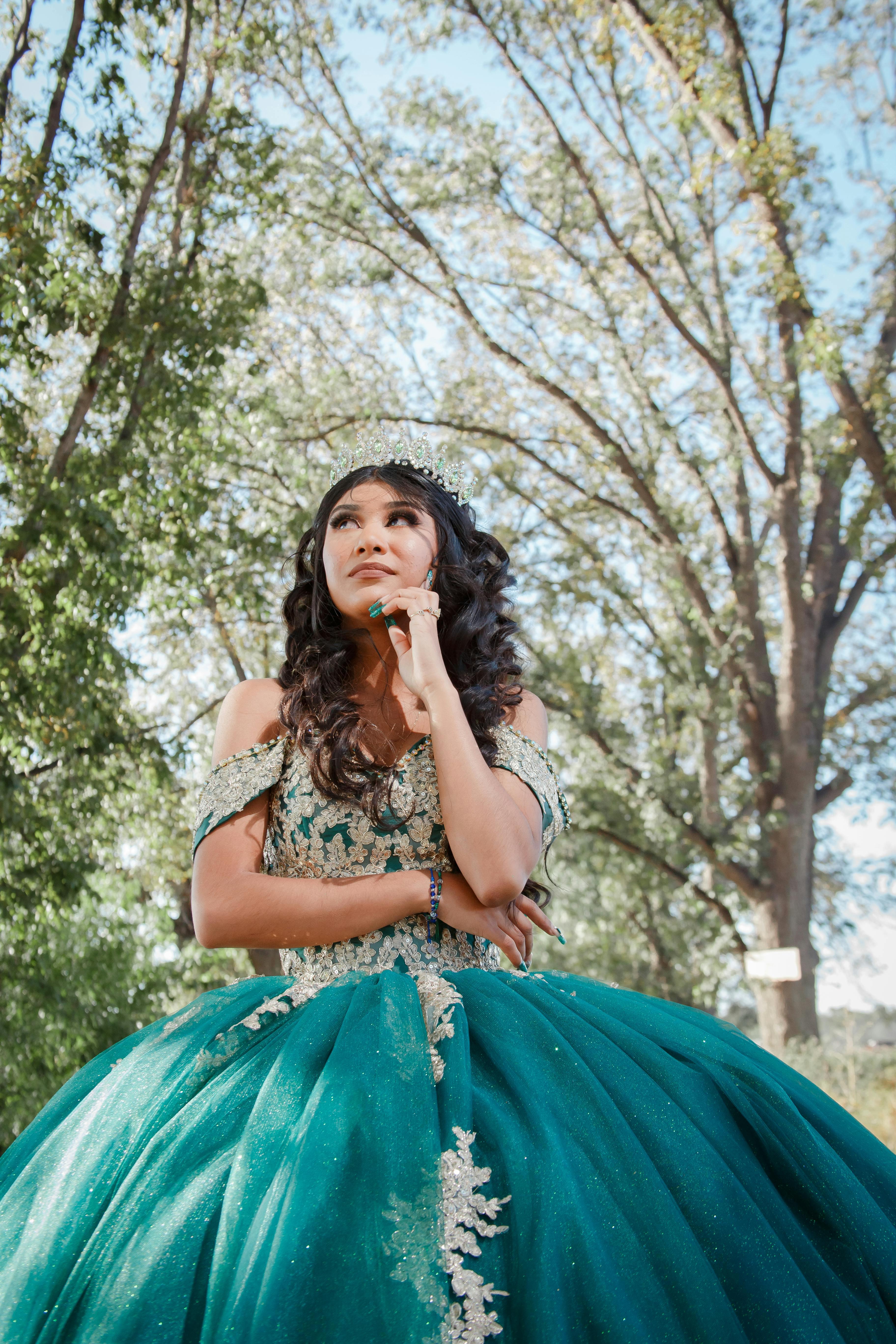 A young woman in a vibrant teal gown embracing her quinceañera amidst nature in Dolores Hidalgo.