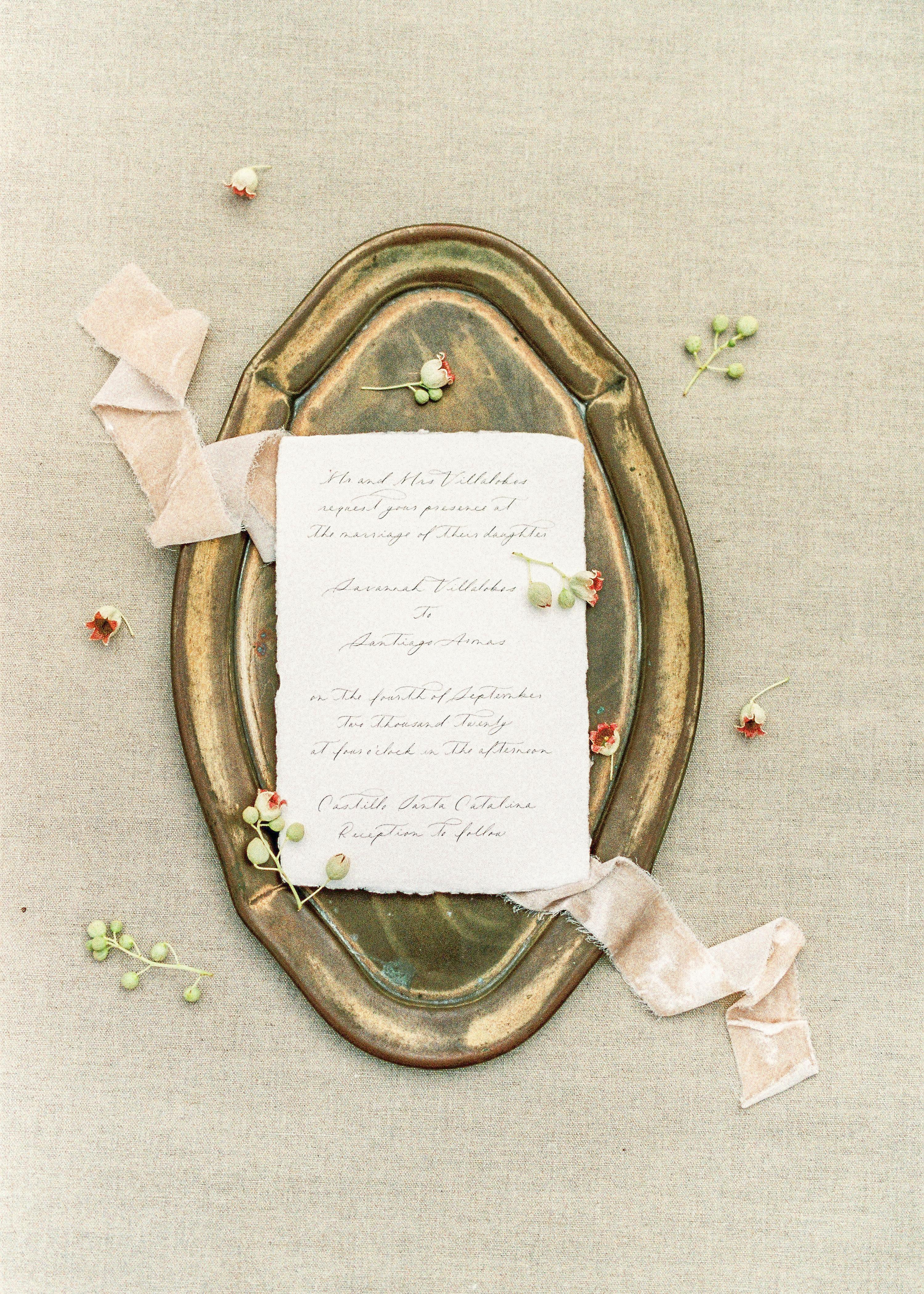 Vintage invitation on brass tray with delicate flowers and ribbon. Perfect for nostalgic or art-themed projects.