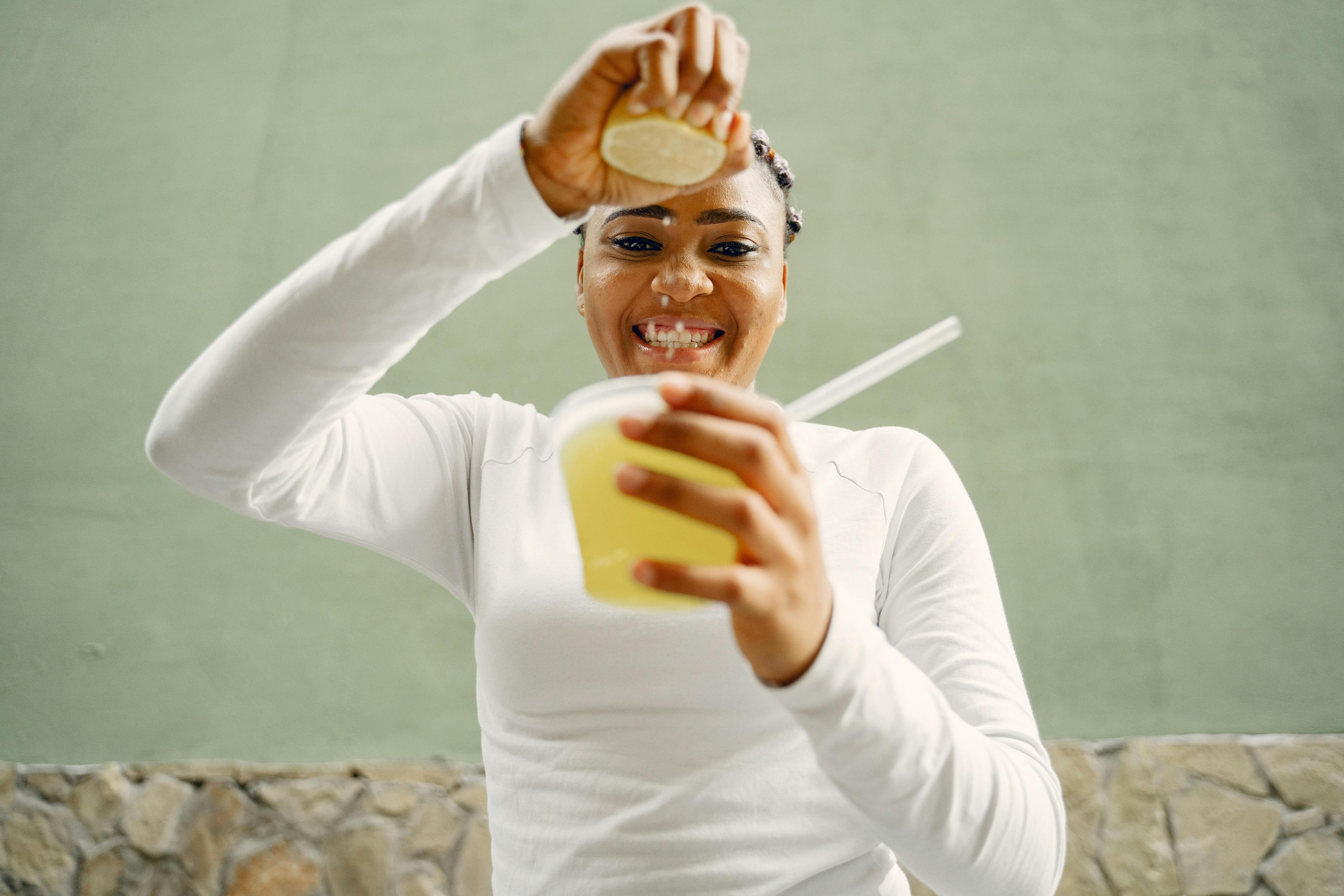 A Woman Squeezing a Lemon Into a Plastic Cup