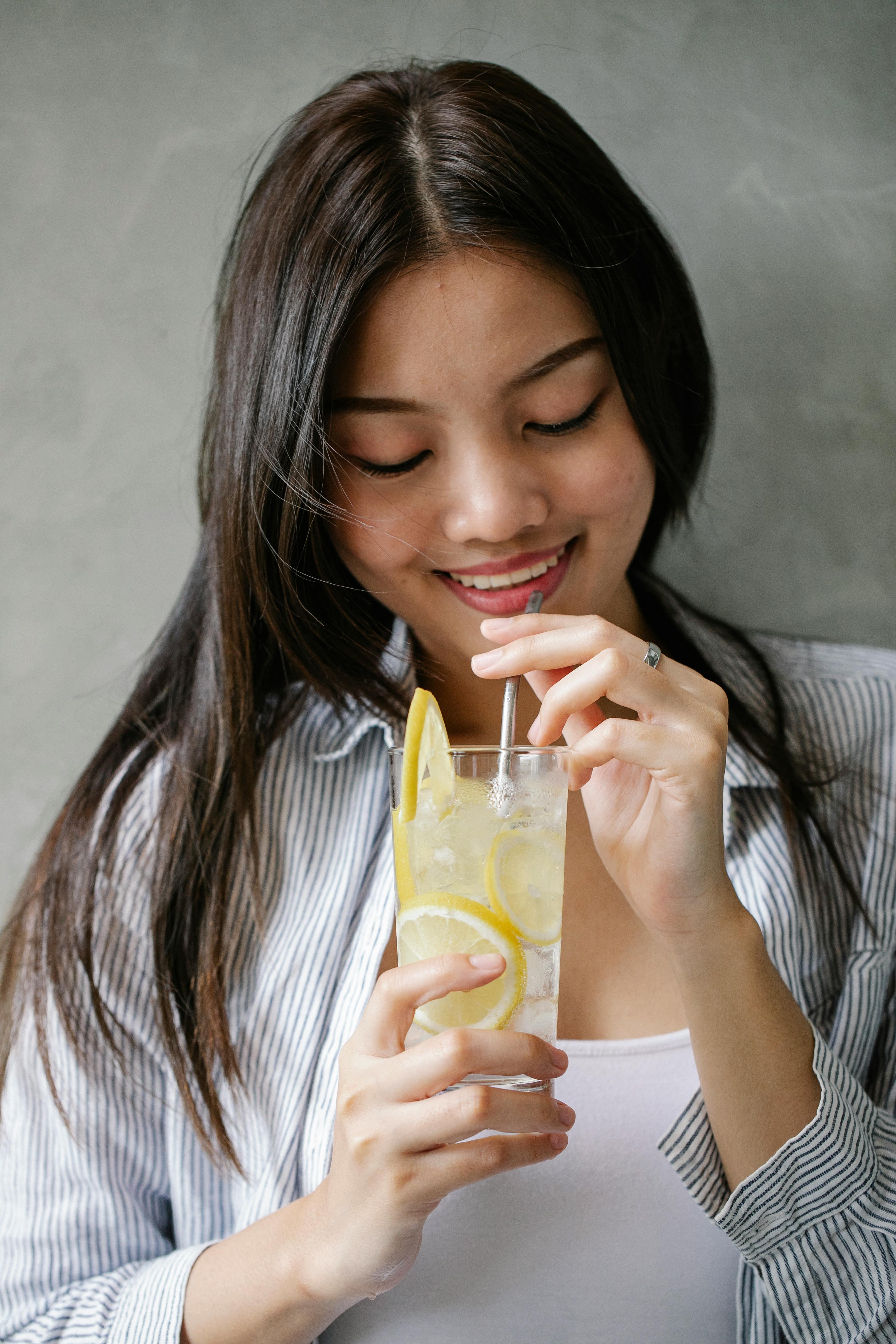 Cheerful Asian woman drinking lemonade