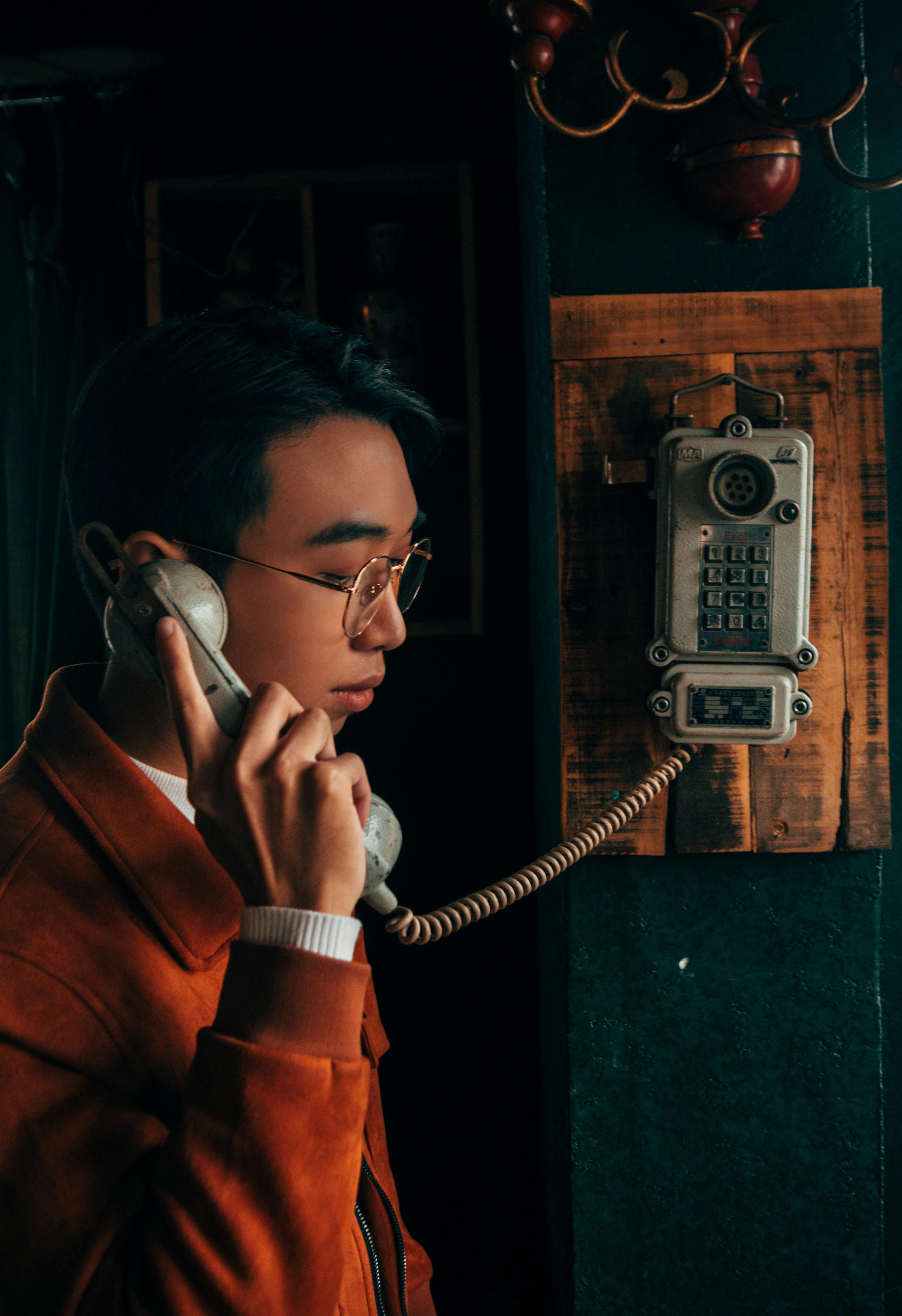 A young man using a vintage rotary phone indoors in Đống Đa, Hanoi.